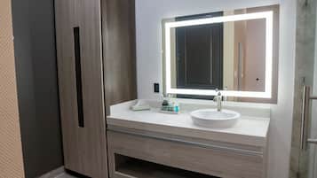 A bathroom with a white sink, a mirror with a light, and wooden cabinets.