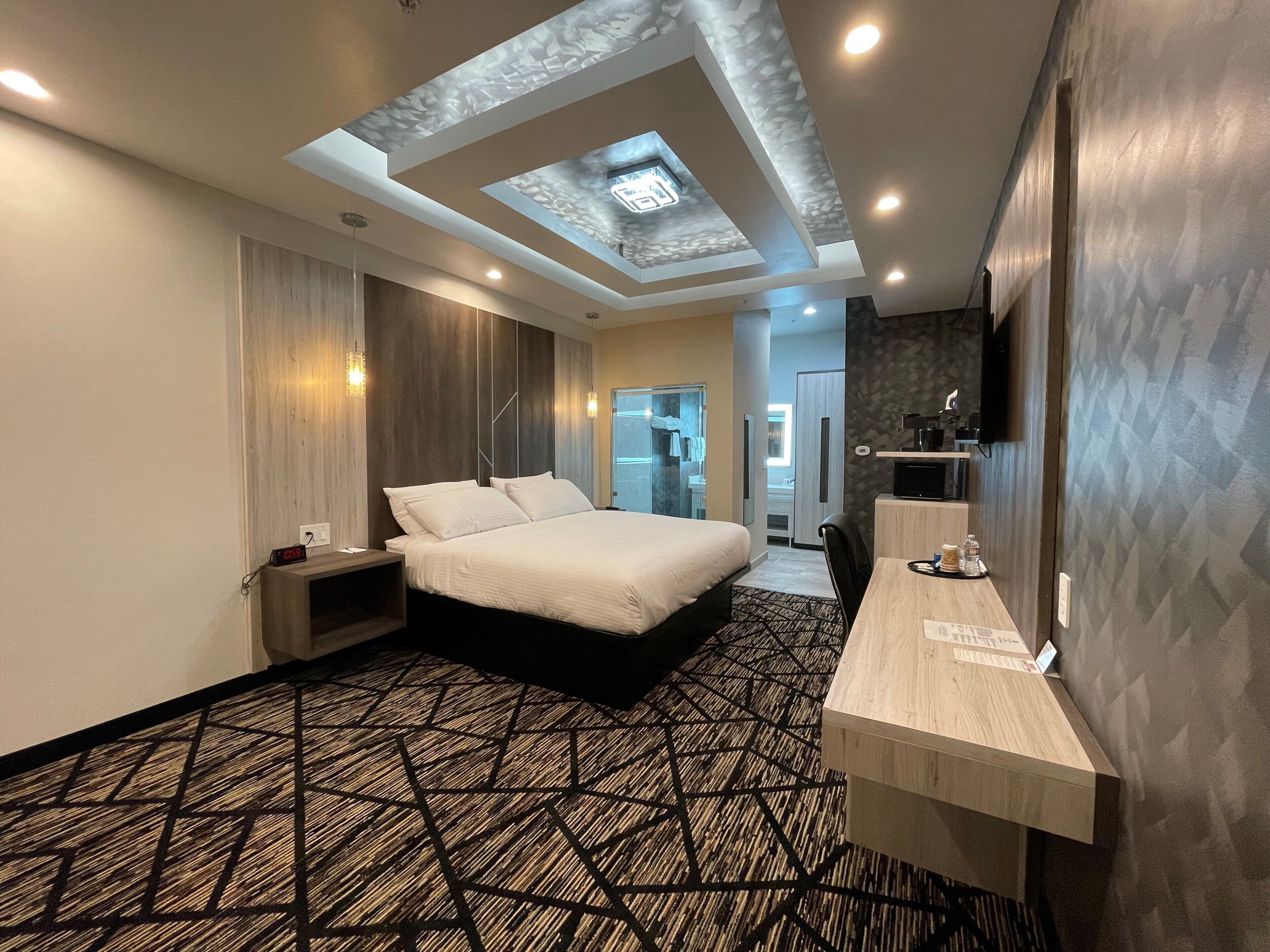 A modern hotel room with a large bed, a desk, and a skylight.