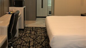 A hotel room with a bed, a desk with a chair, a television, and a microwave. - Comfeeni Inn and Suites (South Houston)
