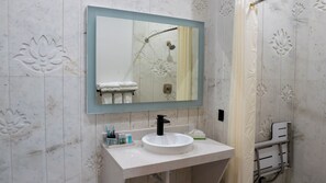 A bathroom with a white sink, a mirror, and a shower.