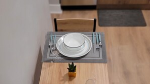 Une table à manger dressée avec des assiettes, des couverts et une petite plante en pot.