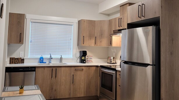 Une cuisine moderne avec des meubles en bois, un réfrigérateur en acier inoxydable et un four encastré.