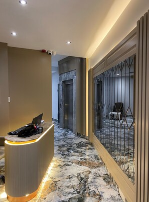 A hotel reception area with a marble floor, a reception desk, and a security camera. - Asilzade Hotel Sirkeci (Istanbul)