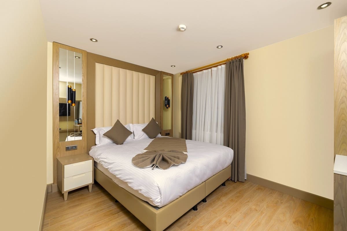 Una habitación de hotel ordenada con cama, mesita de noche y un espejo grande.