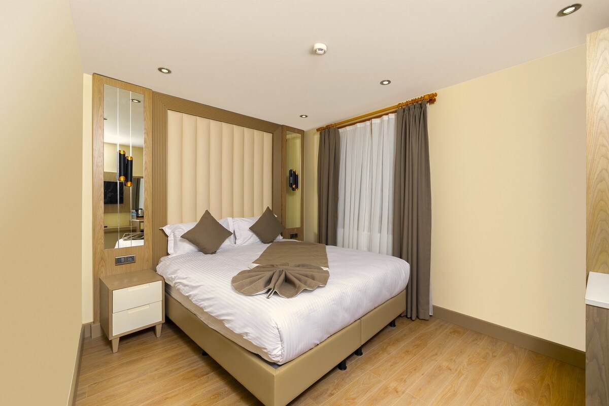 A neatly arranged hotel room with a bed, bedside table, and a large mirror.