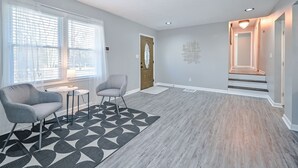 A modern living room with a grey sofa, a patterned rug, and a wooden door. - ***Spacious 4 Bedroom home w 1.1 acre backyard 10 mins Airport*** (atlanta)