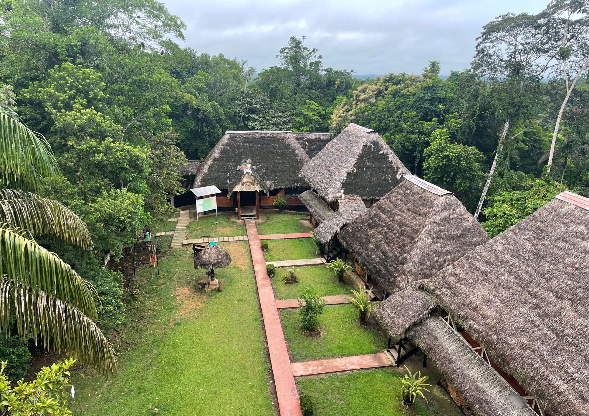 A traditional thatched-roof structure with a central open area and a pathway leading to it.