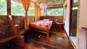 Une pièce en bois avec un lit, un petit tabouret et une fenêtre avec des rideaux.