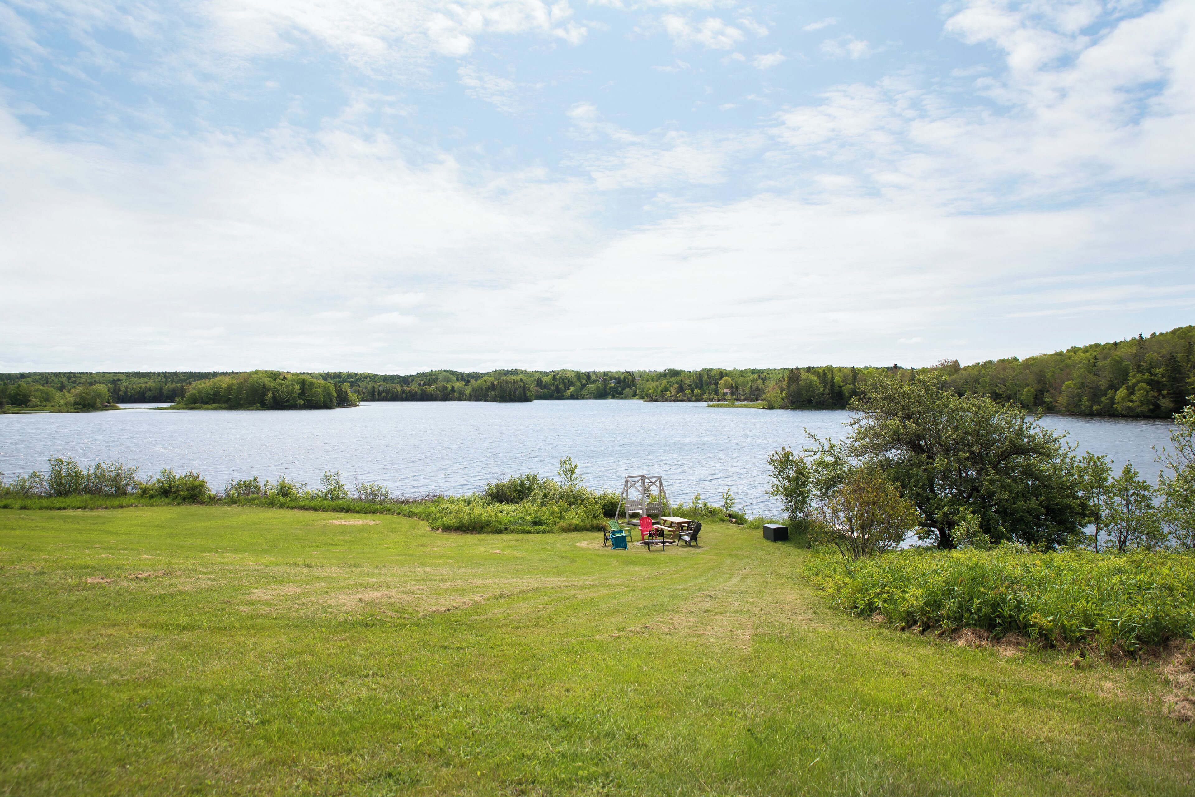 A lakeside view with a grassy area, a swing set, and a picnic table.