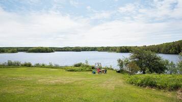 A lakeside view with a grassy area, a swing set, and a picnic table.