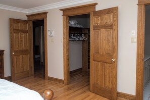 A room with wooden doors, a closet with hanging clothes, and a bed. - Rita’s Retreat Main House ~ Indoor Saltwater Pool ~ with Lake View! (Sydney)