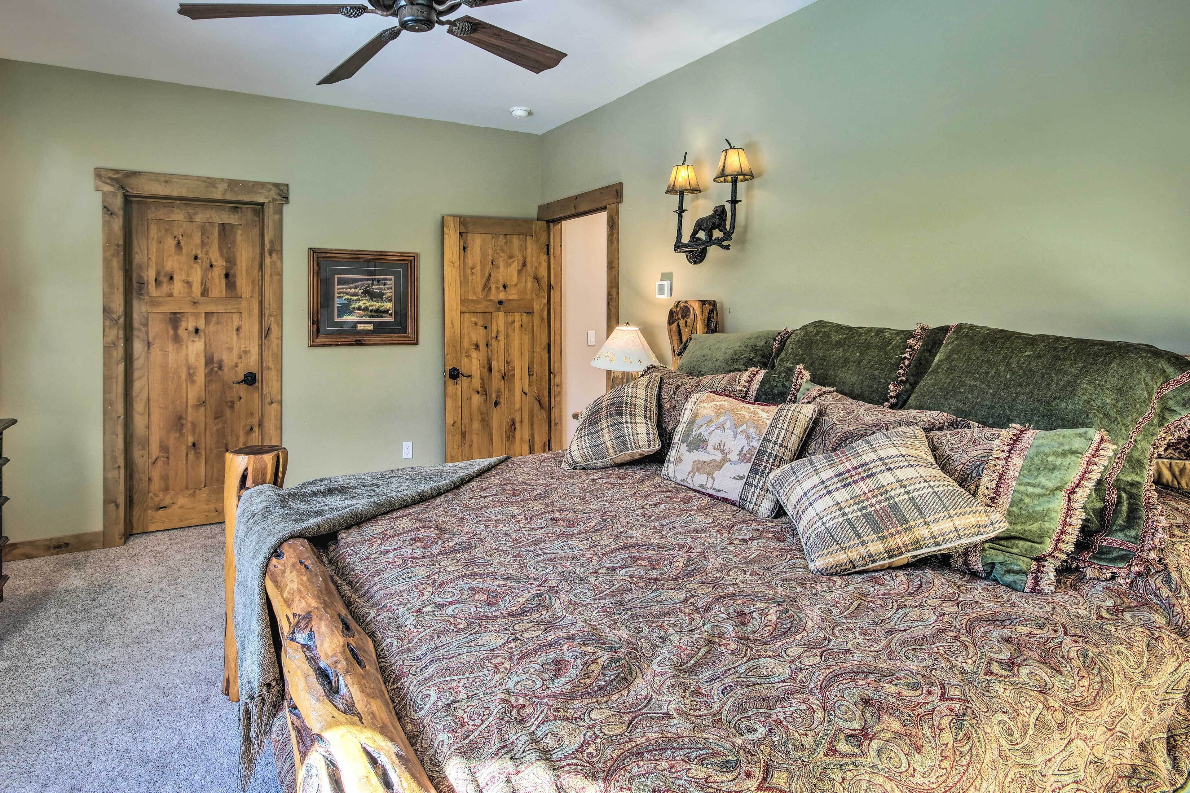 A bedroom with a large bed, two wooden doors, a ceiling fan, and wall-mounted lamps.