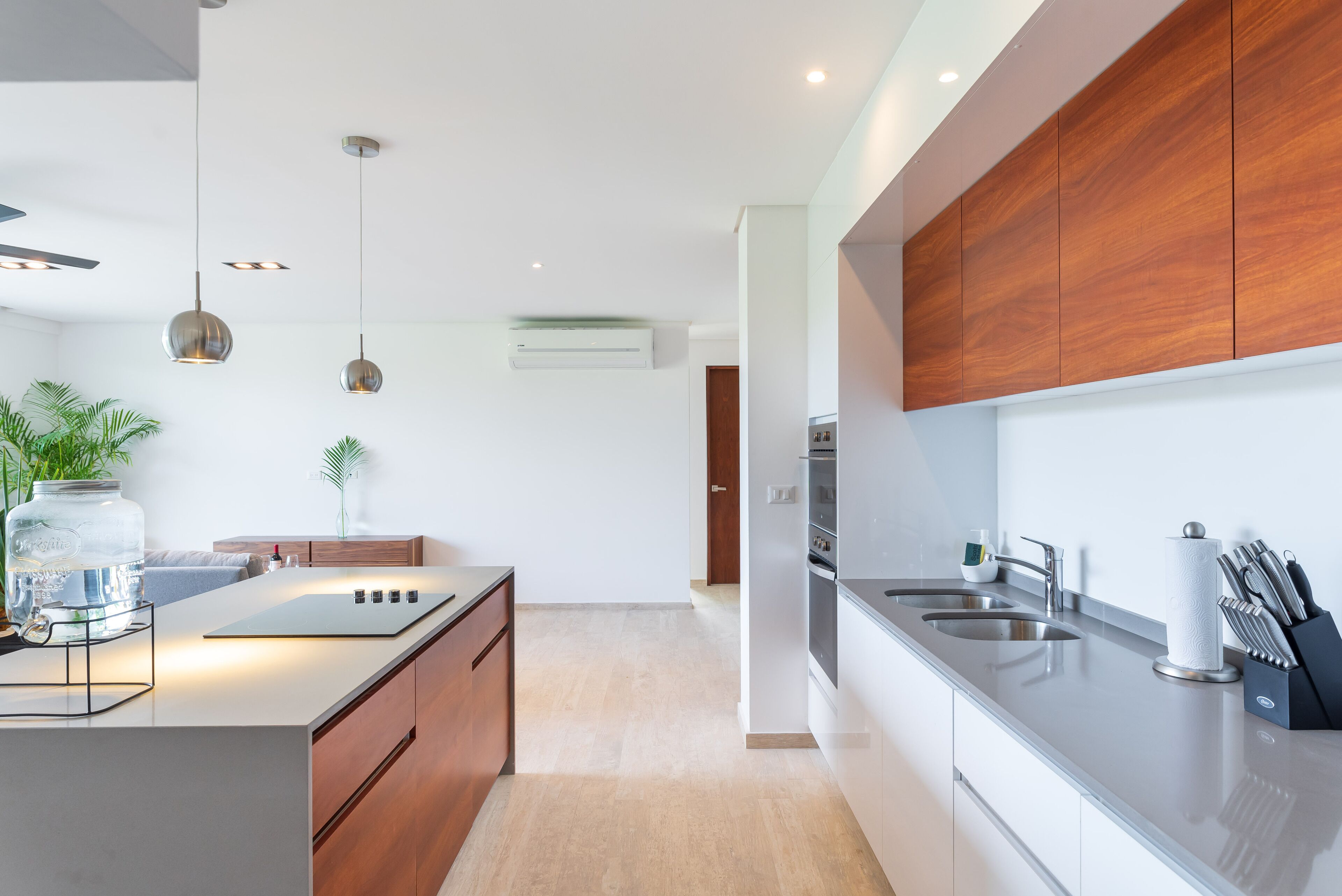 A modern kitchen with a central island, stainless steel appliances, wooden cabinets, and pendant lighting.