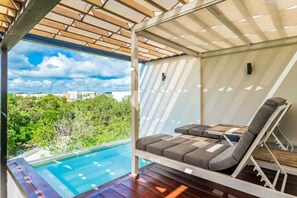 A poolside lounge area with a pergola overhead, a pool, and a view of greenery and buildings. - Panoramic By Alegria Rentals and Sandy Powerful  (Tulum)