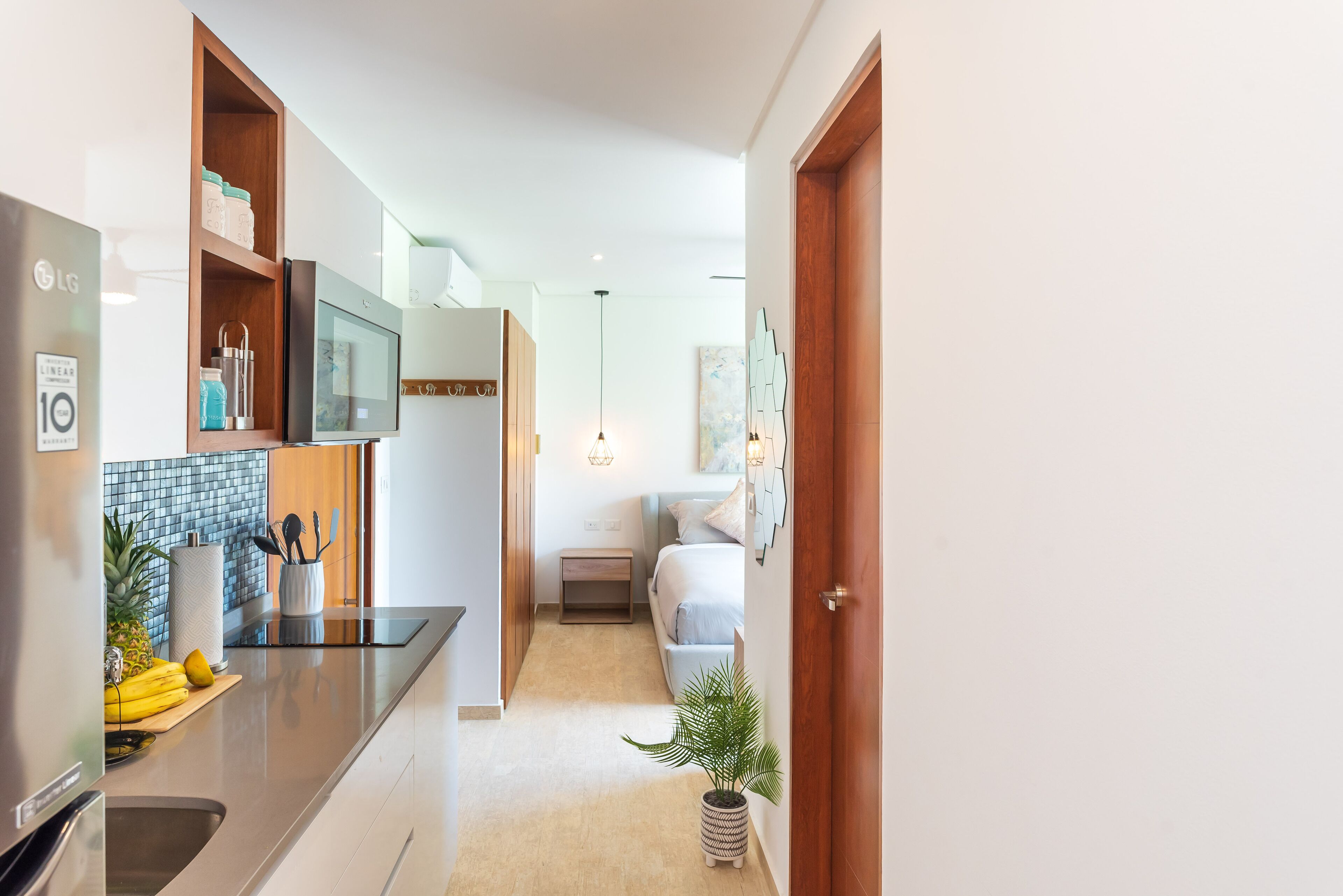 Una cocina moderna con refrigerador, microondas y un estante de madera con utensilios de cocina.