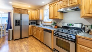 A modern kitchen with wooden cabinets, stainless steel appliances, a dishwasher, and a gas stove. - Home sweet home! (Missoula)