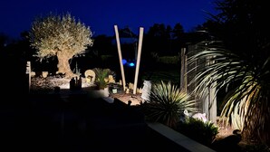 A garden with a large tree, various plants, and a wooden fence.