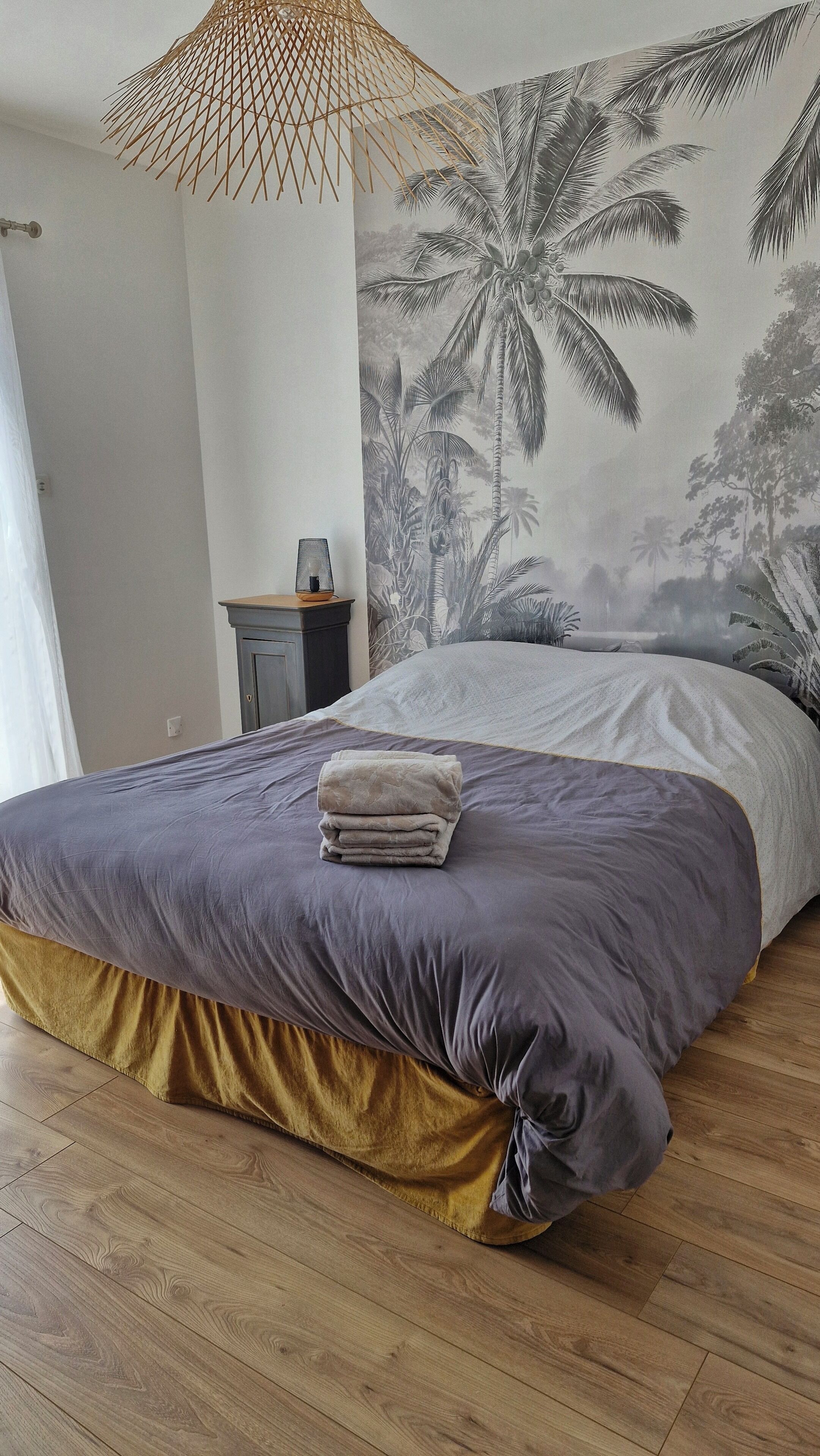 Une chambre à coucher avec un lit, une table de chevet, une lampe et une fresque murale.