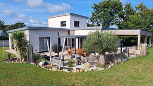 A modern house with a patio, outdoor seating, and a barbecue area.