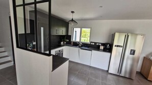 A modern kitchen with white cabinets, a black countertop, and stainless steel appliances.