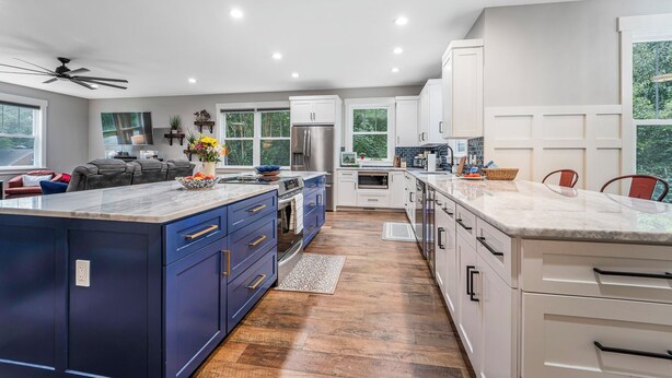Une cuisine moderne dotée d’un grand îlot central, de meubles blancs et d’un plancher en bois.