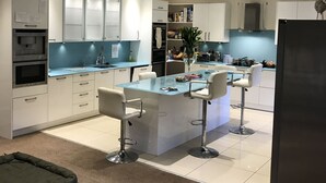 Una cocina moderna con armarios blancos, una isla central con taburetes y un refrigerador.