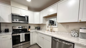A modern kitchen with white cabinets, stainless steel appliances, a microwave, a dishwasher, and a coffee maker. - Prime location, Aurora viewing, Fast WI-FI!! (Fairbanks)