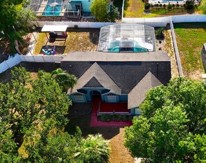 Stylish home with a steeply pitched roof and symmetrical facade, surrounded by a lush garden and a swimming pool.