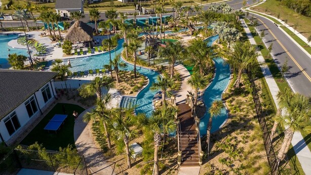Une vue aérienne d’un complexe hôtelier doté de plusieurs piscines, de palmiers et d’une route.