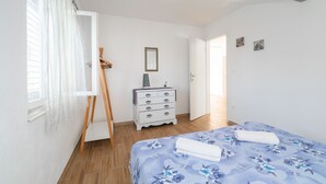 Une chambre à coucher avec un lit, une commode et un tableau accroché au mur.