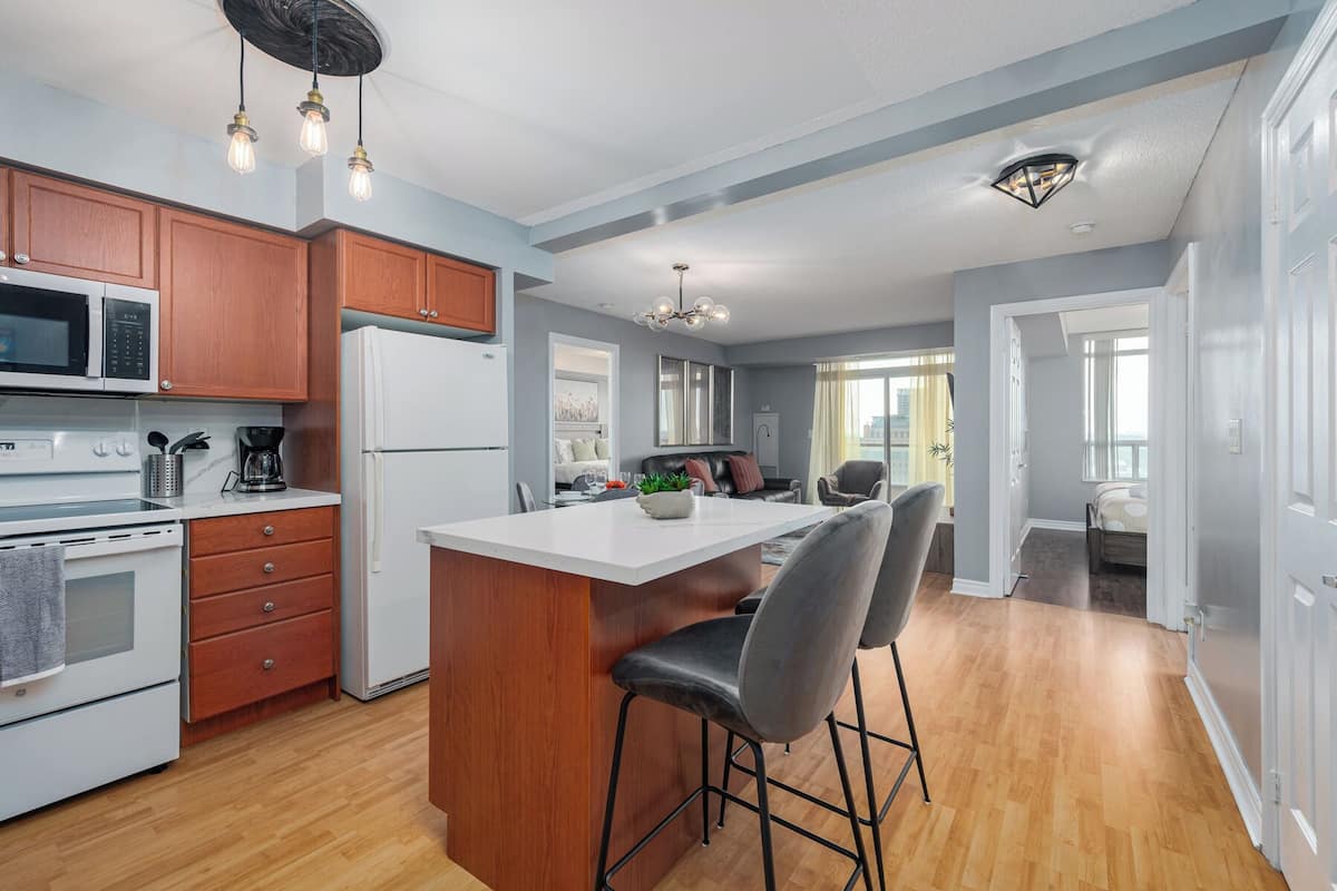 A modern kitchen with wooden cabinets, a white refrigerator, and a central island with bar stools.