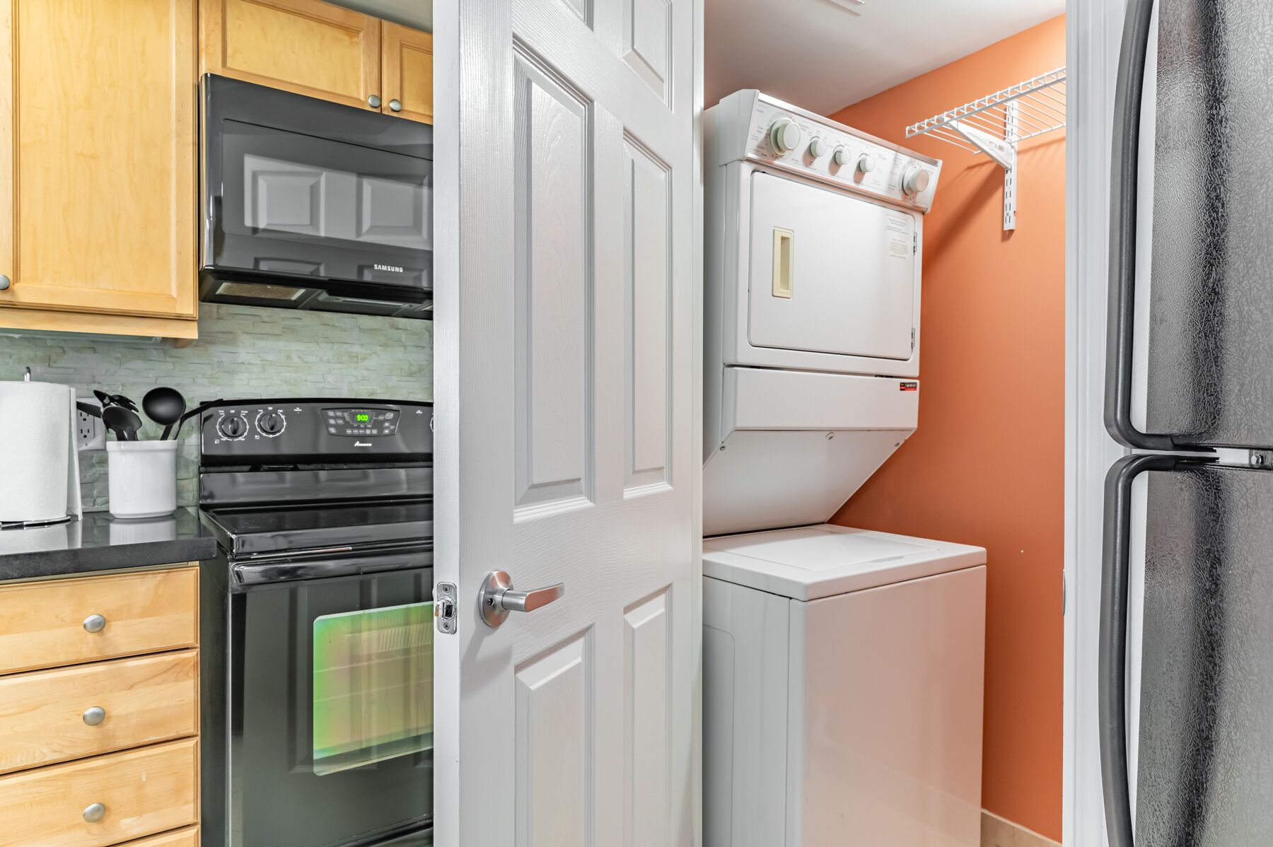 A compact kitchen with a Samsung oven, a washing machine, and a dryer.