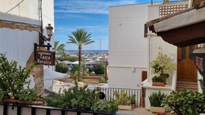 Vista costera con un letrero de restaurante, un edificio blanco y un puerto deportivo al fondo.