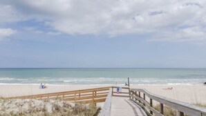 A wooden boardwalk leading to a beach with a clear sky and calm sea. - Spacious 5 BR Home Across from Beach! (Kure Beach)