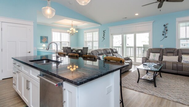 A spacious living area with a large island, a ceiling fan, and a view of the outdoors. - Spacious 5 BR Home Across from Beach! (Kure Beach)
