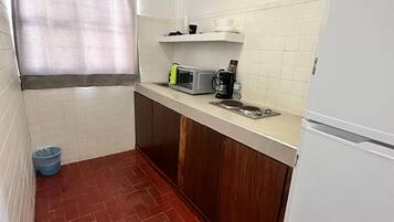 Una cocina compacta con microondas, cafetera y refrigerador.