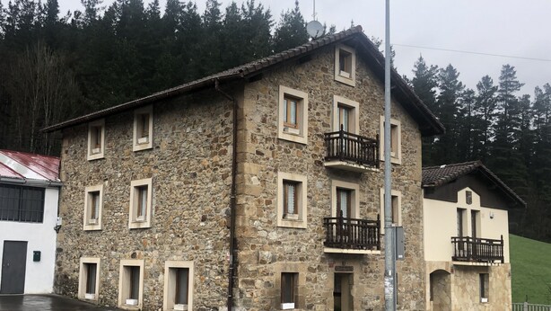 A stone building with multiple windows and balconies, situated on a street with a wet road. - 10 minutes from the Urkiola Natural Park (Izurtza)