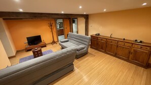 A living room with a grey sofa, wooden cabinets, and a television. - 10 minutes from the Urkiola Natural Park (Izurtza)