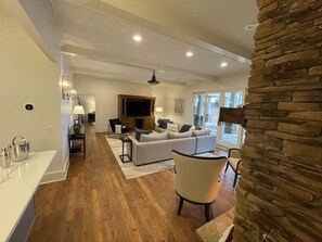 A spacious living area with a large sofa, a dining table, and a kitchen area with a stone accent wall. - Beautiful lakefront property in Reynolds Lake Oconee. (Greensboro)