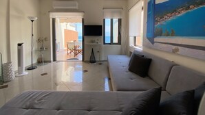 Una sala de estar moderna con un sofá, un televisor y un cuadro de un paisaje costero.