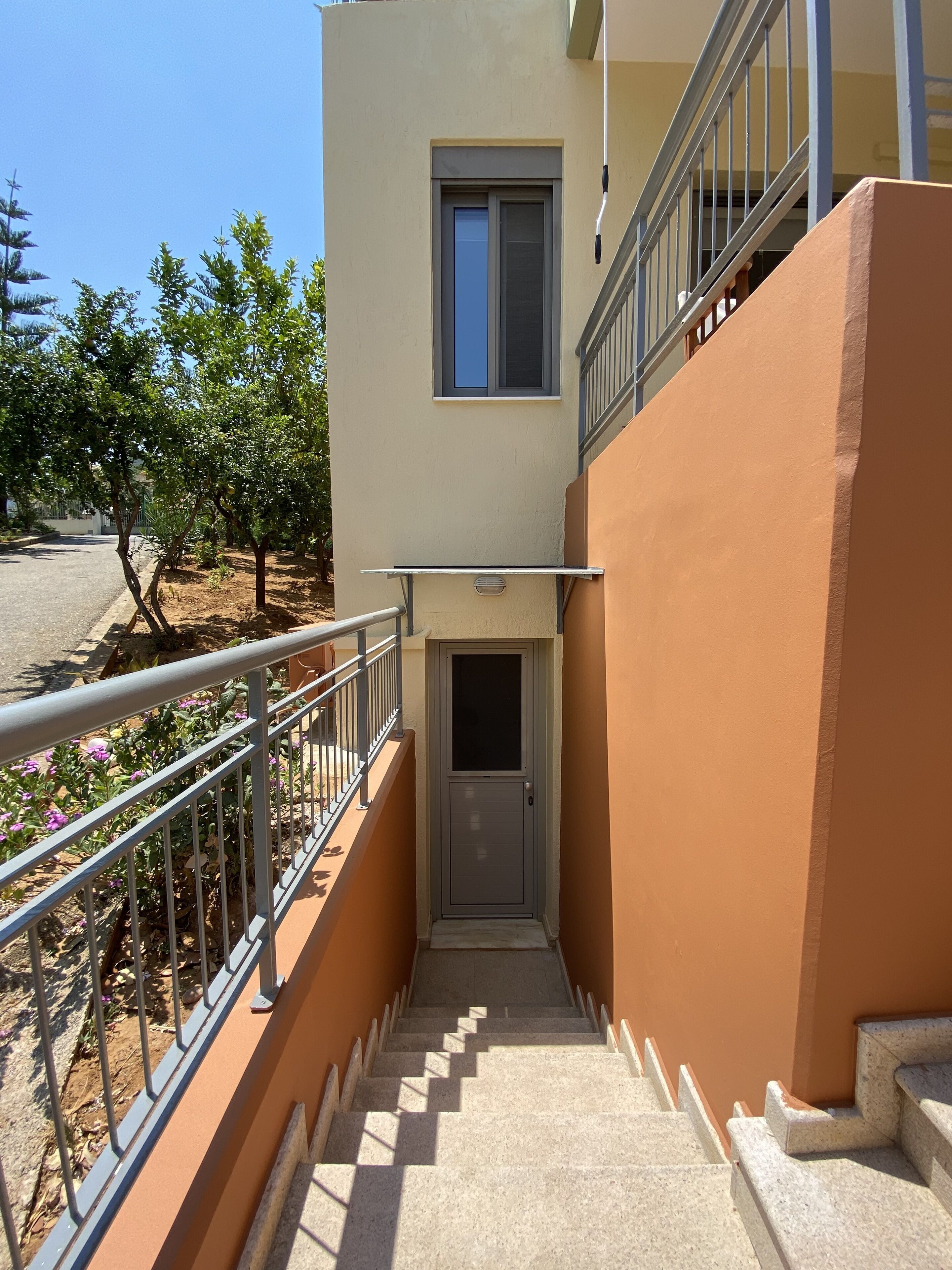 A building with a staircase leading to a door, a small window, and a metal railing.