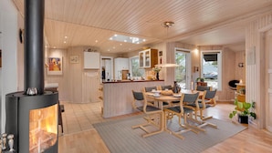 Una cocina moderna con armarios de madera, una isla central y un comedor con sillas y una mesa.