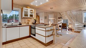Una cocina moderna con una isla central, muebles de madera y lavavajillas integrado.