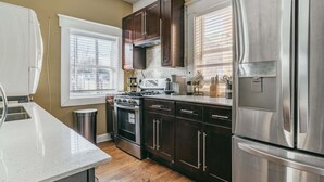 Una cocina moderna con armarios de madera oscura, electrodomésticos de acero inoxidable y un ventanal que proporciona luz natural.