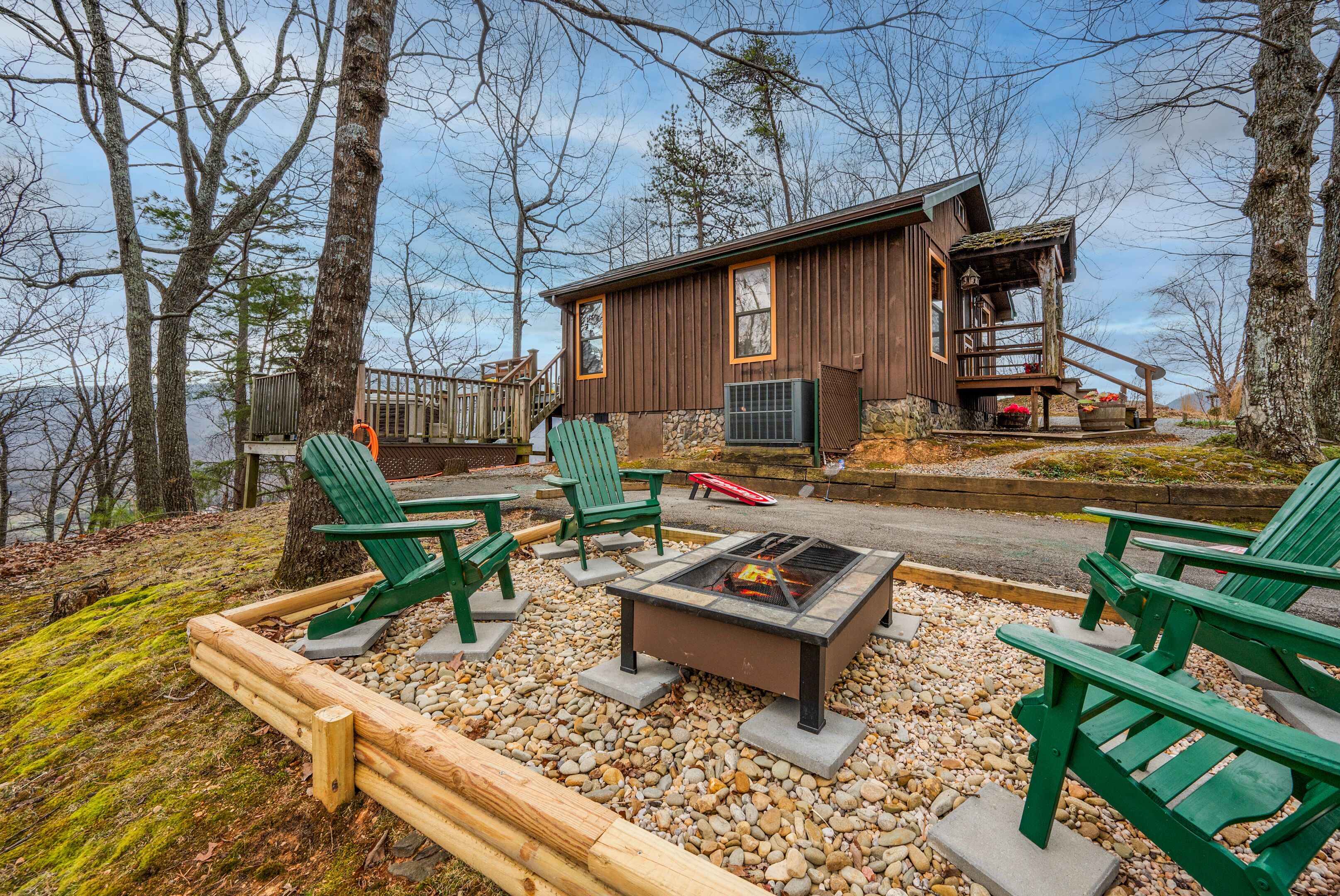 Eine Hütte mit einer Veranda, Sitzgelegenheiten im Freien und einer Feuerstelle.