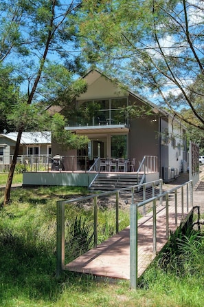 A modern building with a flat roof, large windows, and a covered outdoor seating area. - Serenity HG4: 4Br/3.5Ba with Absolute NP Frontage (Halls Gap)