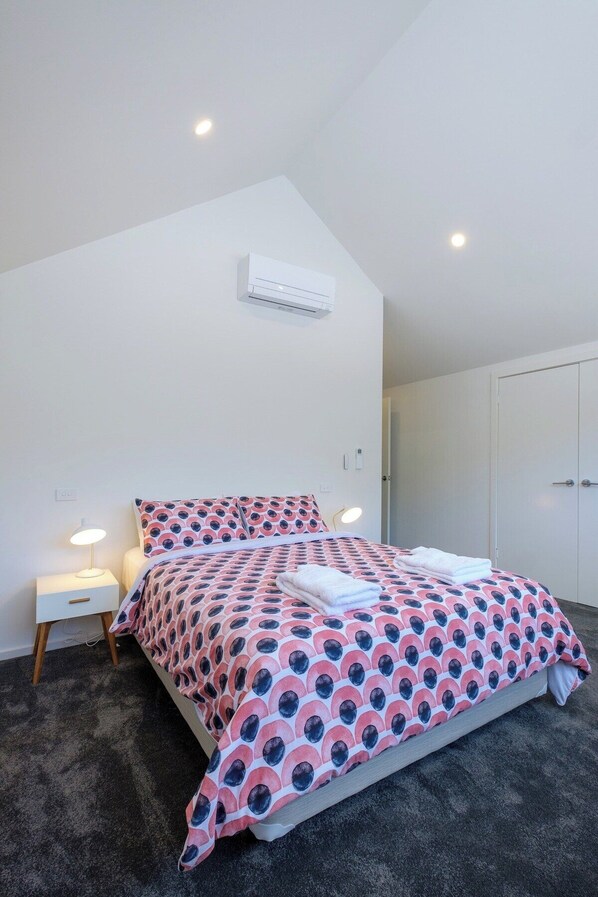 Une chambre à coucher comprenant un lit, des lampes de chevet, un appareil de climatisation et une armoire.