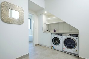 A laundry room with two front-loading washing machines, a towel rack, and a mirror on the wall. - Serenity HG4: 4Br/3.5Ba with Absolute NP Frontage (Halls Gap)