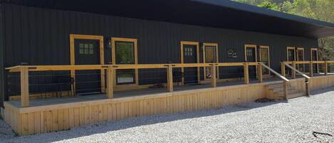 A building with multiple windows, a wooden deck, and a gravel ground.