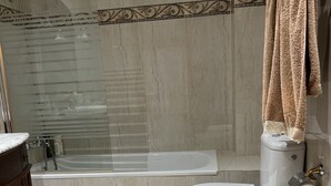 A modern bathroom with a glass-enclosed shower, a bathtub, a toilet, and a bidet.